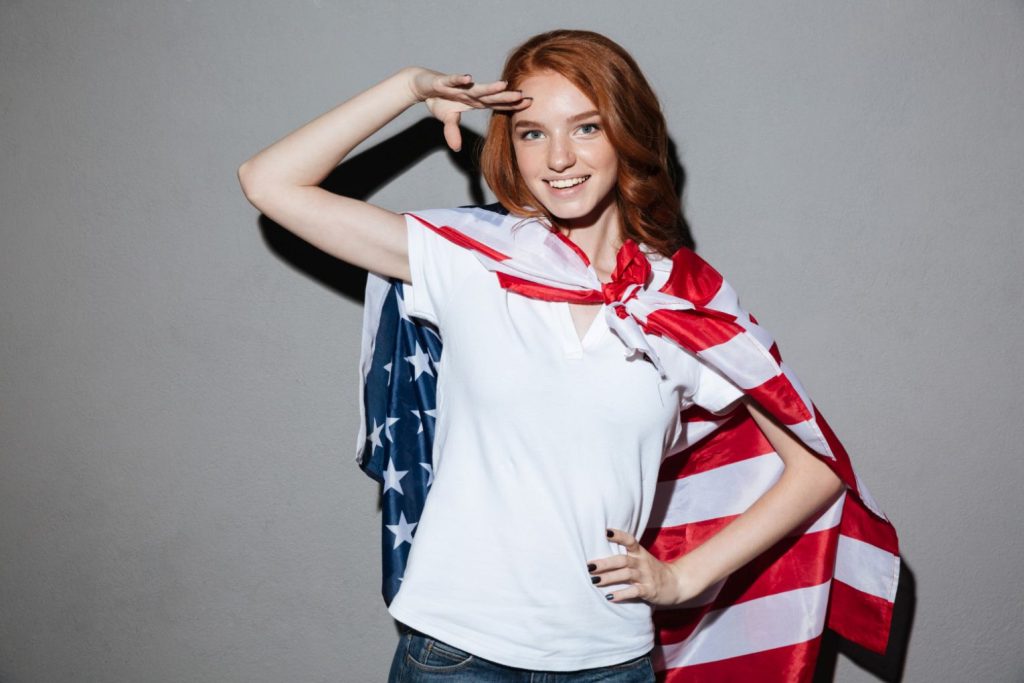 A young woman wearing the American flag around her shoulders as a cape.