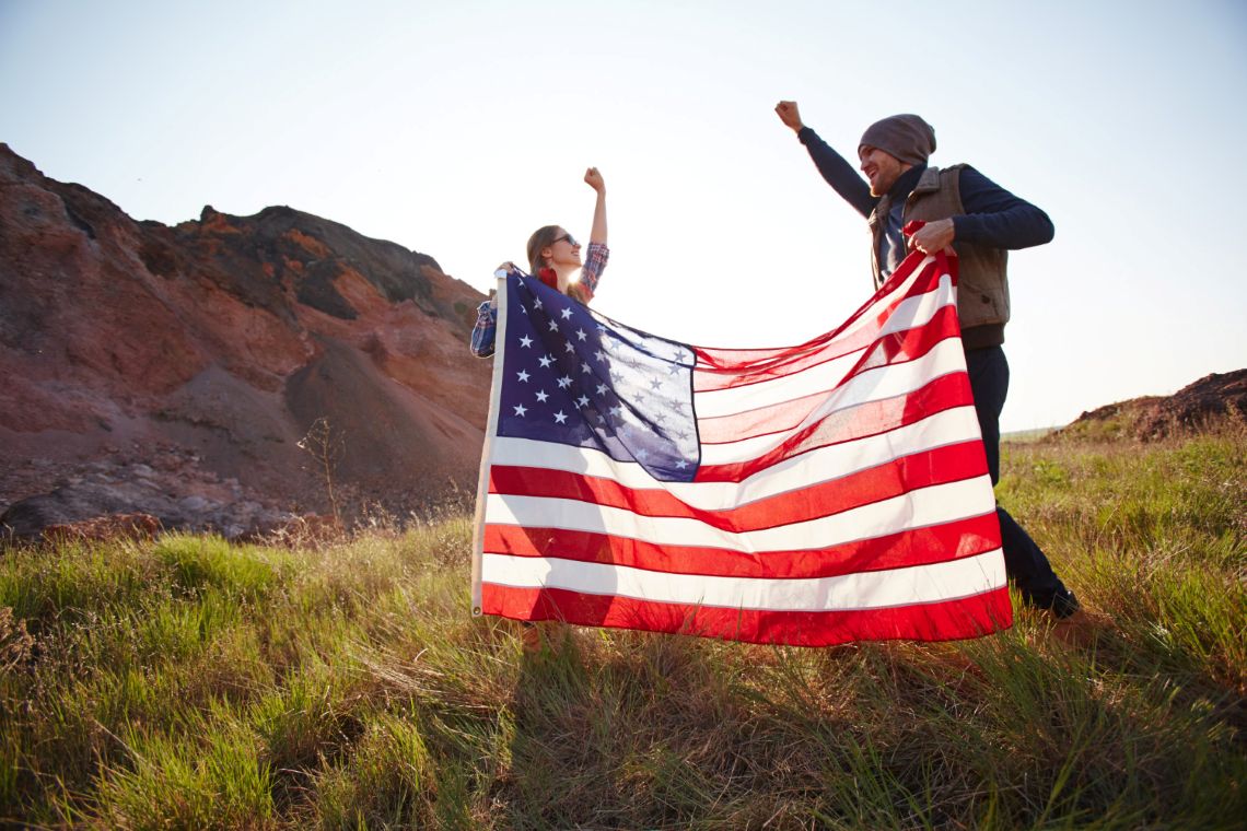 Two people holding up an American flag.